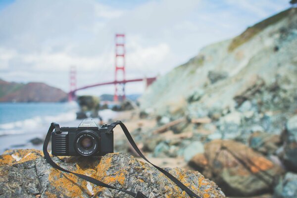 Фотоаппарат canon на камне на фоне моста Золотые ворота