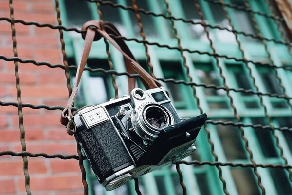 Фотокамера висит на железном заборе