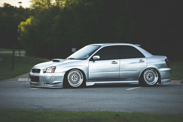Srebrny Subaru na tle drzew