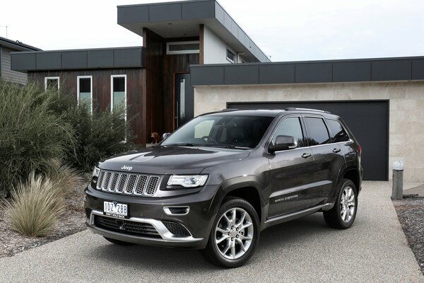 Czarny JEEP GRAND CHEROKEE zaparkowany przed domem