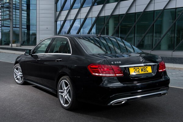 Mercedes-Benzes e 350 czarny zaparkowany obok biurowca