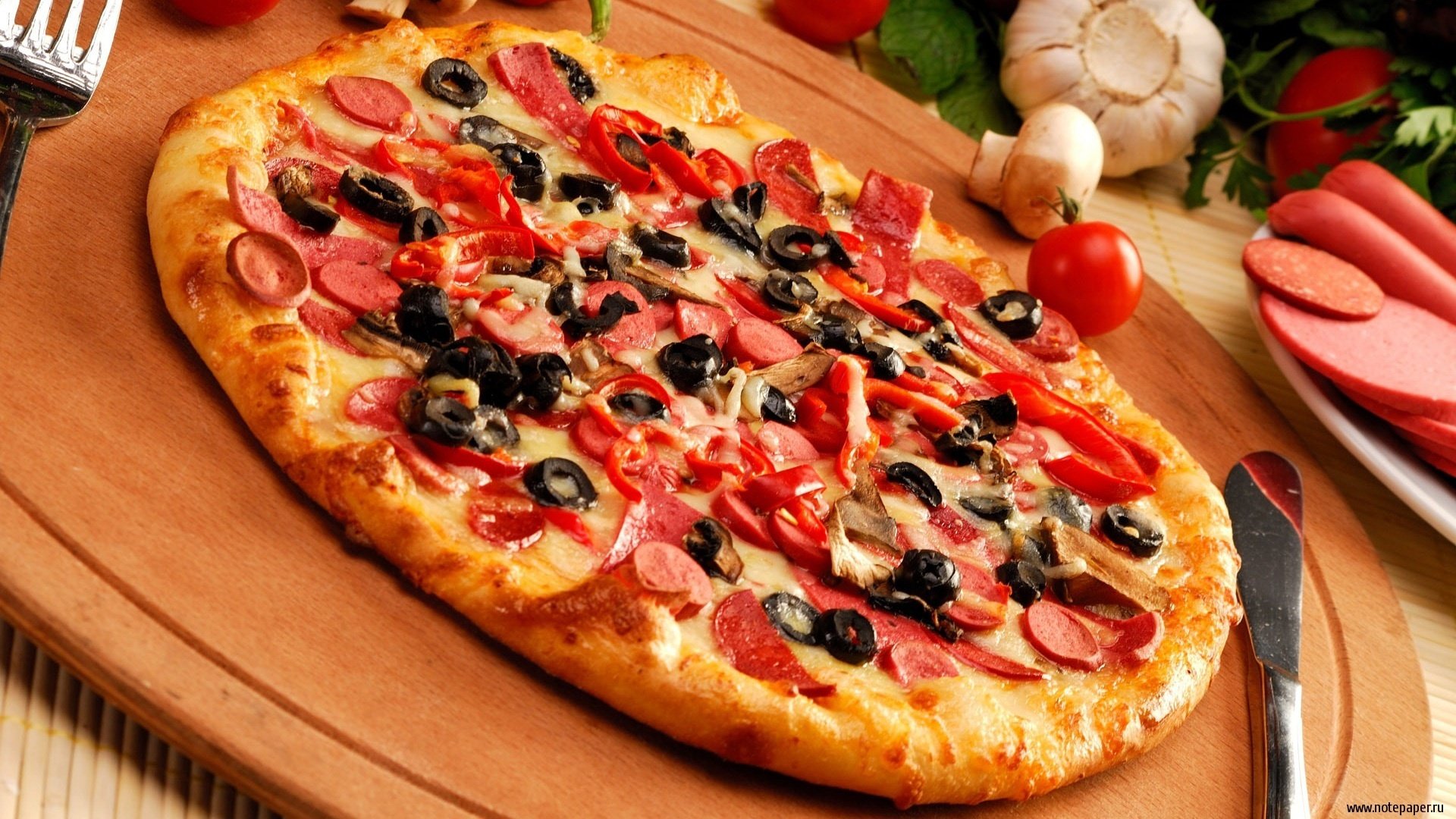jedzenie ciasto pizza kiełbasa czosnek kąt oliwki stół deska nóż przyprawy pizza pomidory oliwki