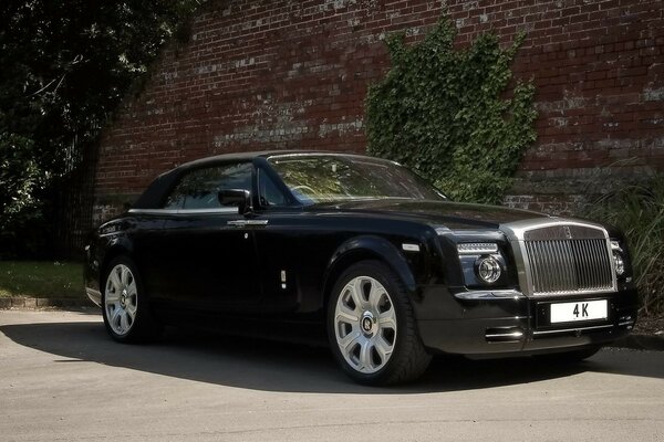 Czarny rolls-royce na tle starej bordowej ściany