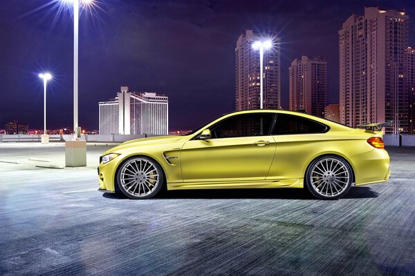 Żółte BMW M4 na tle nocnego miasta