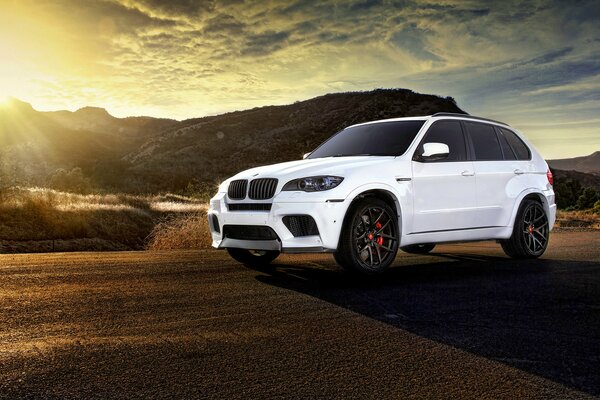 Piękny biały samochód bmw x5 na tle zachodu Słońca