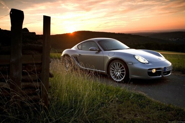 Szary Porsche cayman o zachodzie słońca