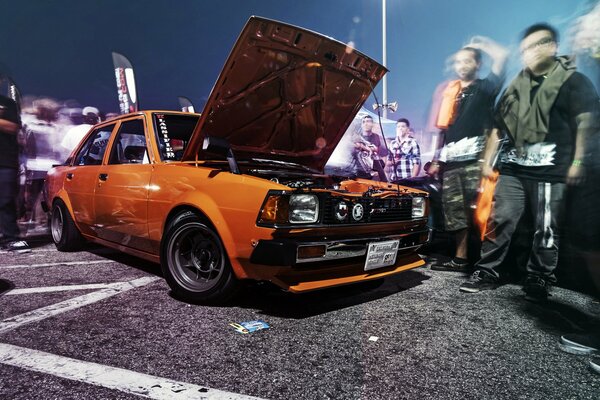 Pomarańczowa Toyota Corolla. Ludzie w ruchu