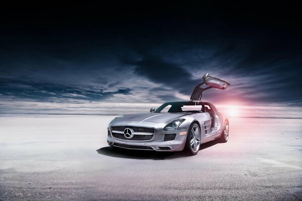 Srebrny Mercedes zatrzymał się na pustyni. Piękno płynących chmur w tle i zachodzące słońce są hipnotyzujące