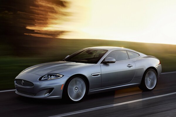 Серебрянный автомобиль Jaguar XK в движении