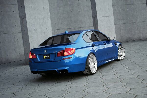 Niebieskie BMW przy szarej ścianie