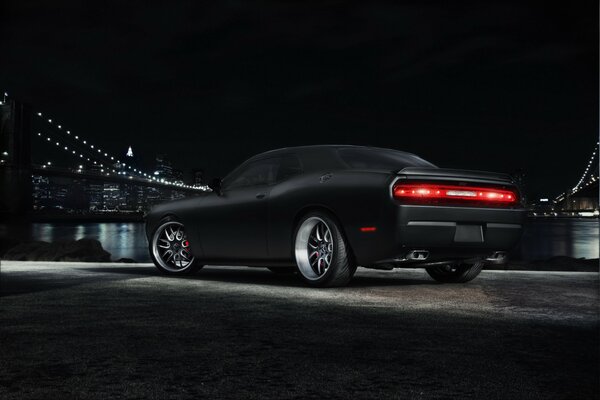 Czarny Dodge Challenger na tle metropolii z mostem