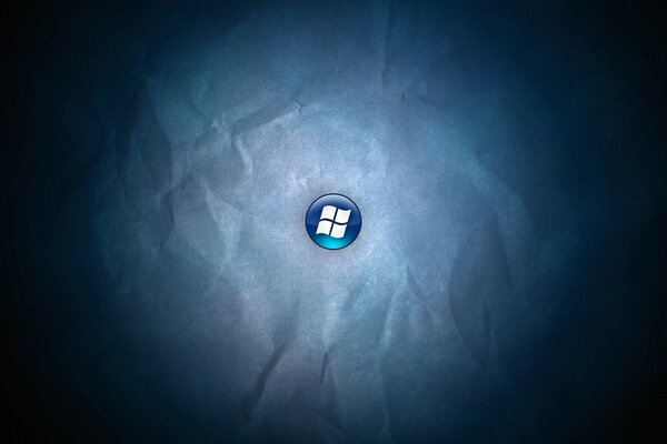 Logo windows na niebieskim przycisku na tle zmiętego papieru