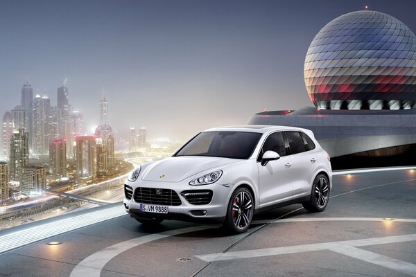 Białe porsche cayenne w pobliżu lądowiska dla helikopterów