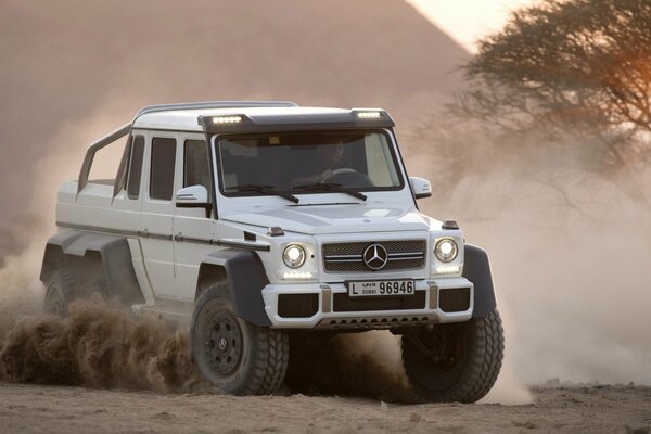 Biały Jeep Mercedes Benz na zakurzonej drodze