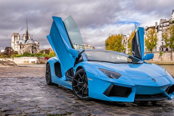 Синий lamborghini на мостовой вечернего Парижа