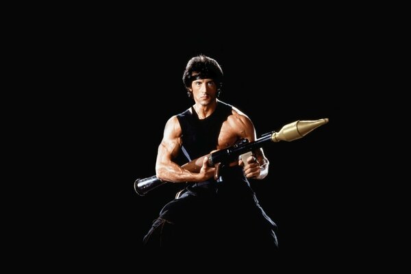 Sylvester Stallone jako Rimbaud na czarnym tle z bronią