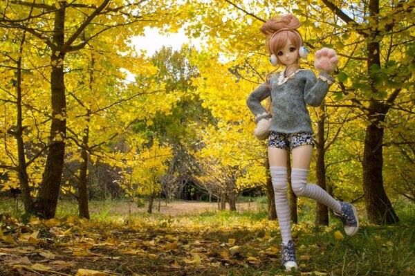 Игрушечная кукла в наушниках и кедах на фоне осеннего парка