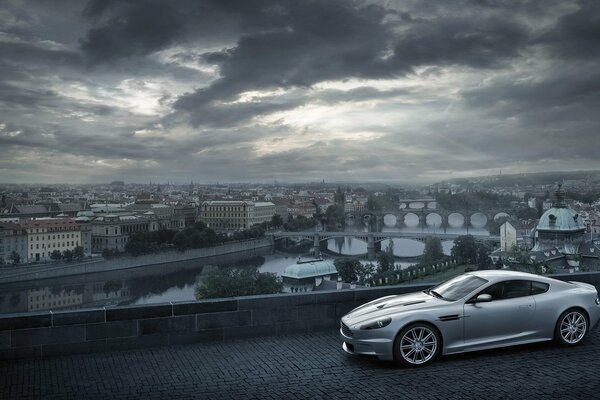 Aston Martin na tle miasta z chmurami