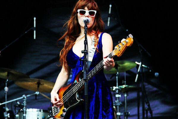 Słynna piosenkarka Jenny Lewis stojąca na scenie i grająca na gitarze
