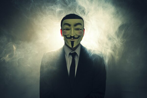 Mężczyzna w dymie, ubrany w strgogy castium i maskę Anonima z filmu v JAK VENDETTA