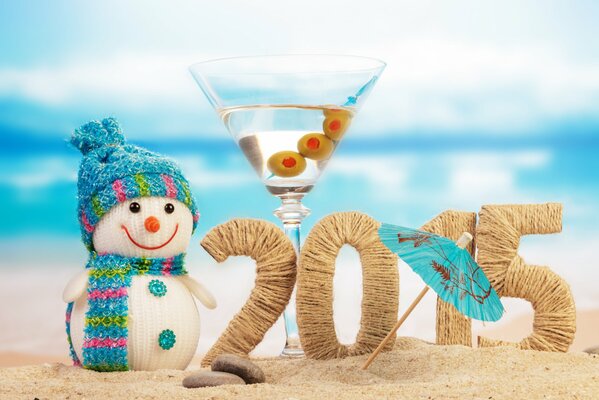 Liczby 2015 na plaży otoczonej bałwanem i kieliszkiem martini z parasolem