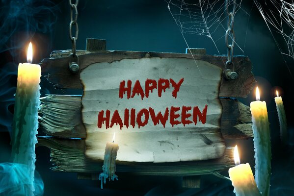 Napis Wesołego Halloween obok świec