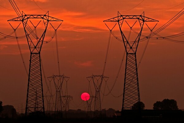 Sylwetki pomostów linii energetycznych o zachodzie słońca